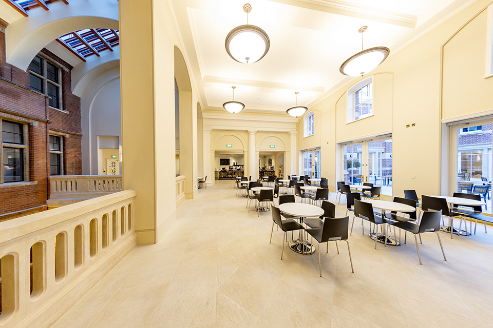 A shot of the RCM cafe, with several small white round tables, and black chairs.